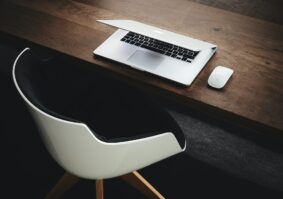 empty desk chair, desk and partially closed laptop