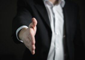 man in suit reaching out to shake a hand in alternative dispute resolution