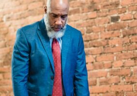 Unhappy older man in suit near brick wall